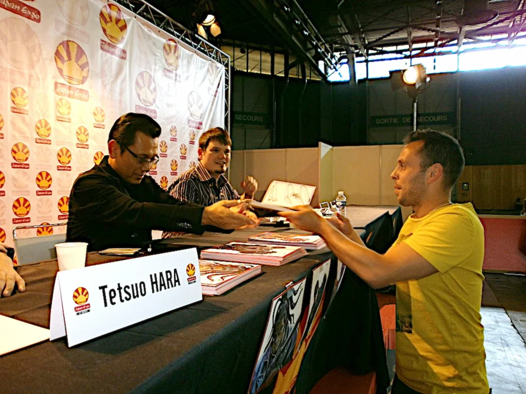 photo ou l'on voit julien GOMEZ le président de la galerie du manga recevoir le premier tome hokuto no ken dedicacé des mains de Tetsuo HARA